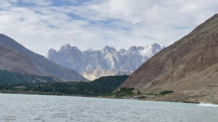 Profile view of breathtaking landscape view of mountain range at background with Attabad lake in front in Hunza, Pakistan.