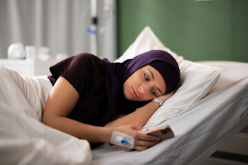 Arab patient engrossed in her phone, browsing through uplifting messages from loved ones,