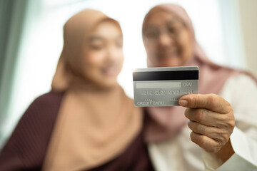 Muslim mother and daughter holding a credit card