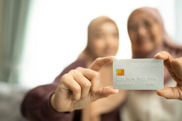 Two muslim woman holding a credit card