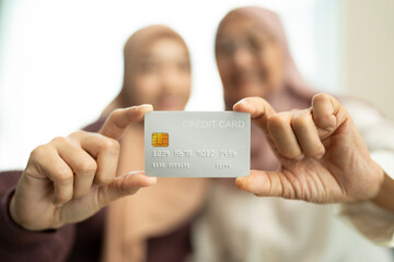 Two muslim woman holding a credit card