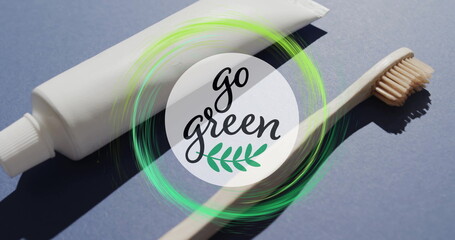 Image of go green text and green ring over toothpaste tube and wooden toothbrush