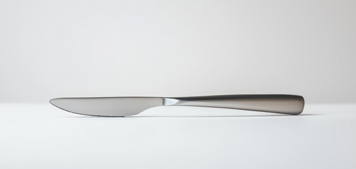 Sleek table knife with a smooth stainless steel finish, isolated on a white surface, simple and modern cutlery design