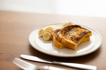 朝日の差し込む窓辺で、木製のテーブルの上に置かれたフレンチトースト