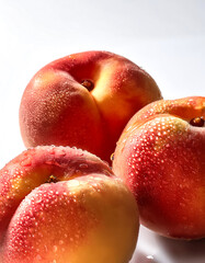 Close-up of fresh Peaches with water droplets on a solid white background