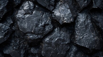 Dark textured rock surface with irregular shapes and shadows.