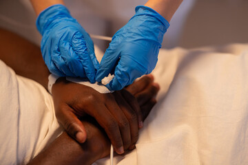 Close-up shot showcases doctor's hand meticulously assessing the catheter of the African patient.