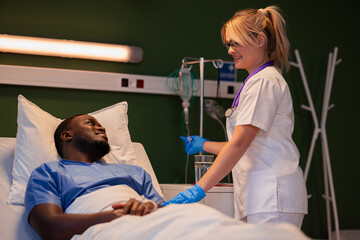 Doctor's assistant stands by the patient, making sure the IV catheter is secure.