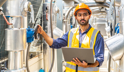 Asian male technical foreman inspects maintenance of turn off the water pipe and looking data in laptop computer, Emergency, plumbing and electrical systems on the roof of a building