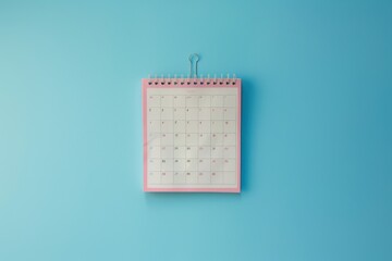 A colorful desk calendar hanging against a bright blue wall, marking important dates and events for the month ahead