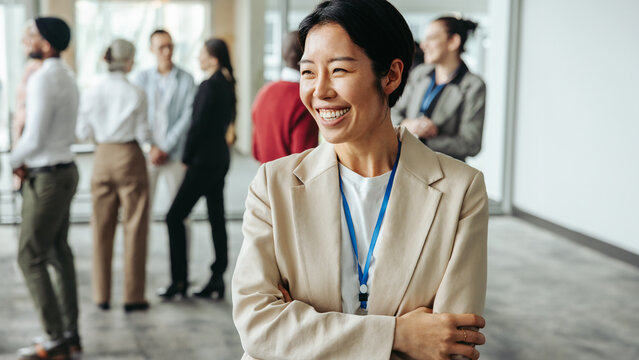 Happy professional woman smiling as diverse group engages in networking event within modern office environment