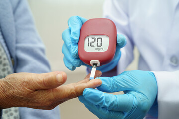 Asian doctor using digital glucose meter for check sample blood sugar level to treatment diabetes.