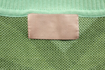 Brown blank laundry care clothes label on green shirt fabric background