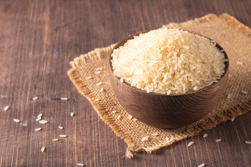 Uncooked white rice in a wooden bowl. Healthy cereal concept.  