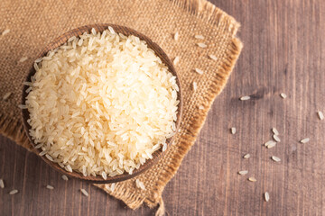 Uncooked white rice in a wooden bowl. Healthy cereal concept.  