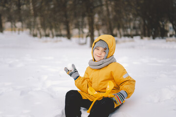 Young boy playing with a snowball maker in a cold winter day