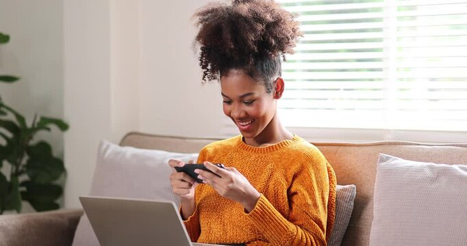 Portrait of stylish Happy african american woman in afro hair using phone on sofa 
