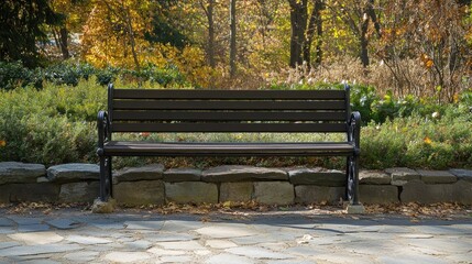 Empty wooden bench with metal frame in a park with stone pathway.