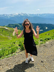 Naklejka premium A tourist girl in a black dress in the mountains
