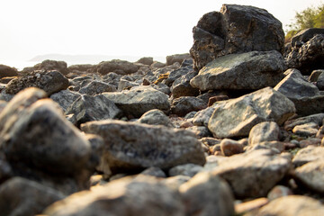 A rocky beach with a large rock in the foreground. Rocky texture and calm day scene.