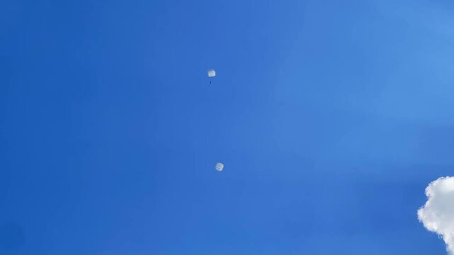 Parachutists descend from a cloudy sky