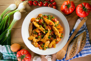 Sautéed chicken strips with vegetables and tomato sauce. Top view table with  decoration.