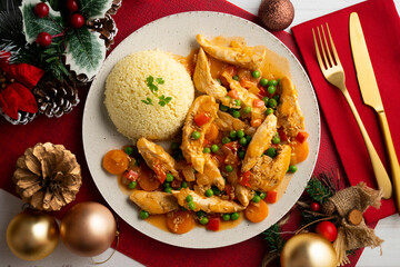 Sautéed chicken strips with vegetables and tomato sauce. Top view table with Christmas decoration.