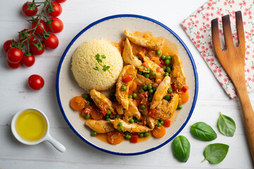 Sautéed chicken strips with vegetables and tomato sauce. Top view table with  decoration.