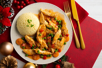Sautéed chicken strips with vegetables and tomato sauce. Top view table with Christmas decoration.