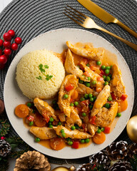 Sautéed chicken strips with vegetables and tomato sauce. Top view table with Christmas decoration.