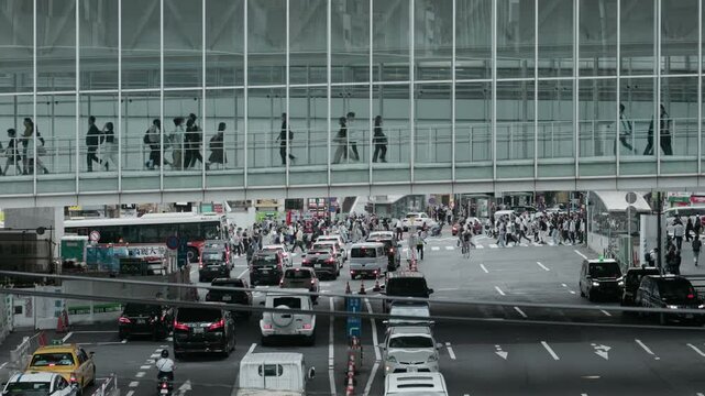 Tokyo Scene : People Walking on a Connecting Footbridge Over an Urban Highway with a Busy Intersection Visible in the Distance  |  Shibuya Station, Tokyo, Japan