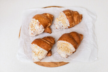 fresh croissants on wooden tray on white table, top view