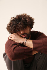 Sleepy young bearded man posing in the studio. Mind set and mental health. Vertical.