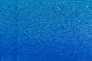 Close-up of a light blue wall spray painted with blue. Abstract full frame textured grunge graffiti background with copy space.