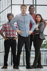 Fototapeta premium male teamleader standing with crossed arms with coworkers in background