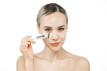 A young woman gently applies cream to her face with a brush. This tender touch emphasizes the importance of skincare and self-care, creating an atmosphere of relaxation and harmony.