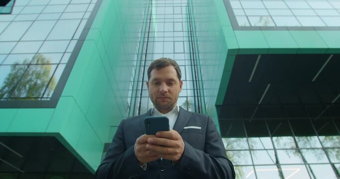 Low view Handsome Startup Businessman in using mobile Phone. Young man texting Messages, cheating on his Smartphone near business center. Business. Social Networking. People. Apps.