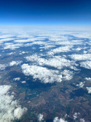 Airplane window view. Clouds, green land, landscape as seen through window of an airplane 