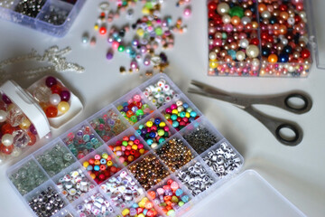 Colorful beads, letter beads, threads and other jewelry making supplies on white background. Making...