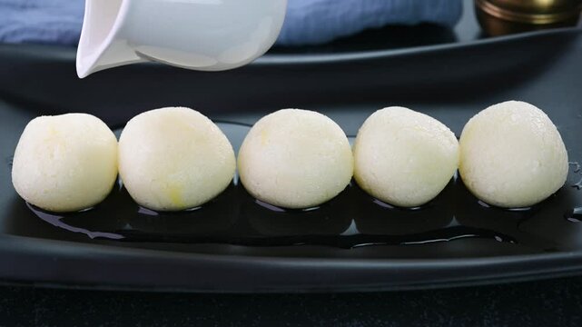 Pouring sugar syrup on rasgulla indian sweet.