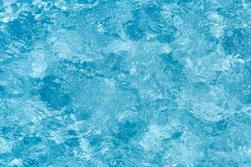 Blue water with ripples on the surface. Defocus blurred transparent blue colored clear calm water surface texture with splashes and bubbles. Water waves with shining pattern texture background.