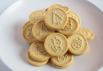round cookies with various designs on them, including Christmas themed symbols like trees, snowmen, and other festive characters. vanilla or butter flavored sandwich cookies.