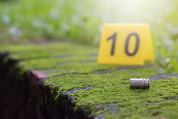 Pistol bullet shell and blurred number 10 on yellow paper on cement floor which has bright green...