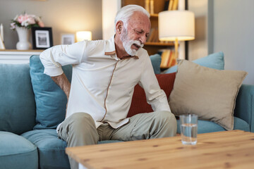 Home, sofa and man holding back for pain, accident or injury with muscle sprain for scoliosis....