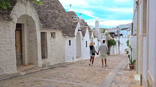 A delightful couple strolls handinhand through the quaint and charming streets of Alberobello, surrounded by the iconic trulli buildings that define the landscape of Puglia in Italy