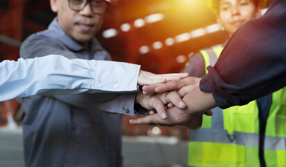 Group of male and female factory workers standing putting their hands together in industry factory. Factory workers stack of hands in factory. Unity and teamwork concept