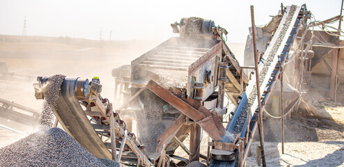 Vibrating screen stone crusher in operation. Crushing stones in a quarry for processing minerals, cement, limestone. Heavy and mobile equipment in a quarry for processing stone into building material.