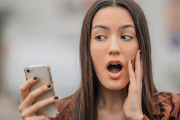 surprised girl looking at mobile phone or smartphone