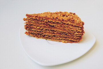 Slice of delicious homemade Medovik or Russian Honey Cake on white background. Layer sponge cake with baked condensed milk covered with crumbs. Popular dessert in countries of the former Soviet Union.