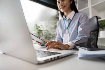 Professional Businesswoman Working on Laptop in Modern Office Environment with Natural Light and Greenery